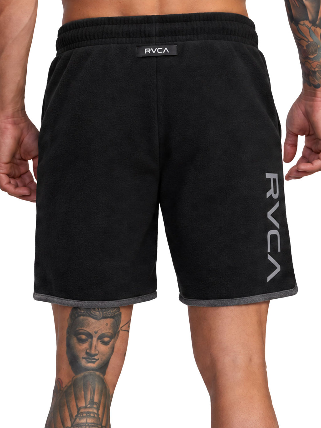 Black athletic shorts with a gray ribbed hem, featuring a vertical white RVCA logo on the left leg and a small black brand tab at the waistband. Back View.