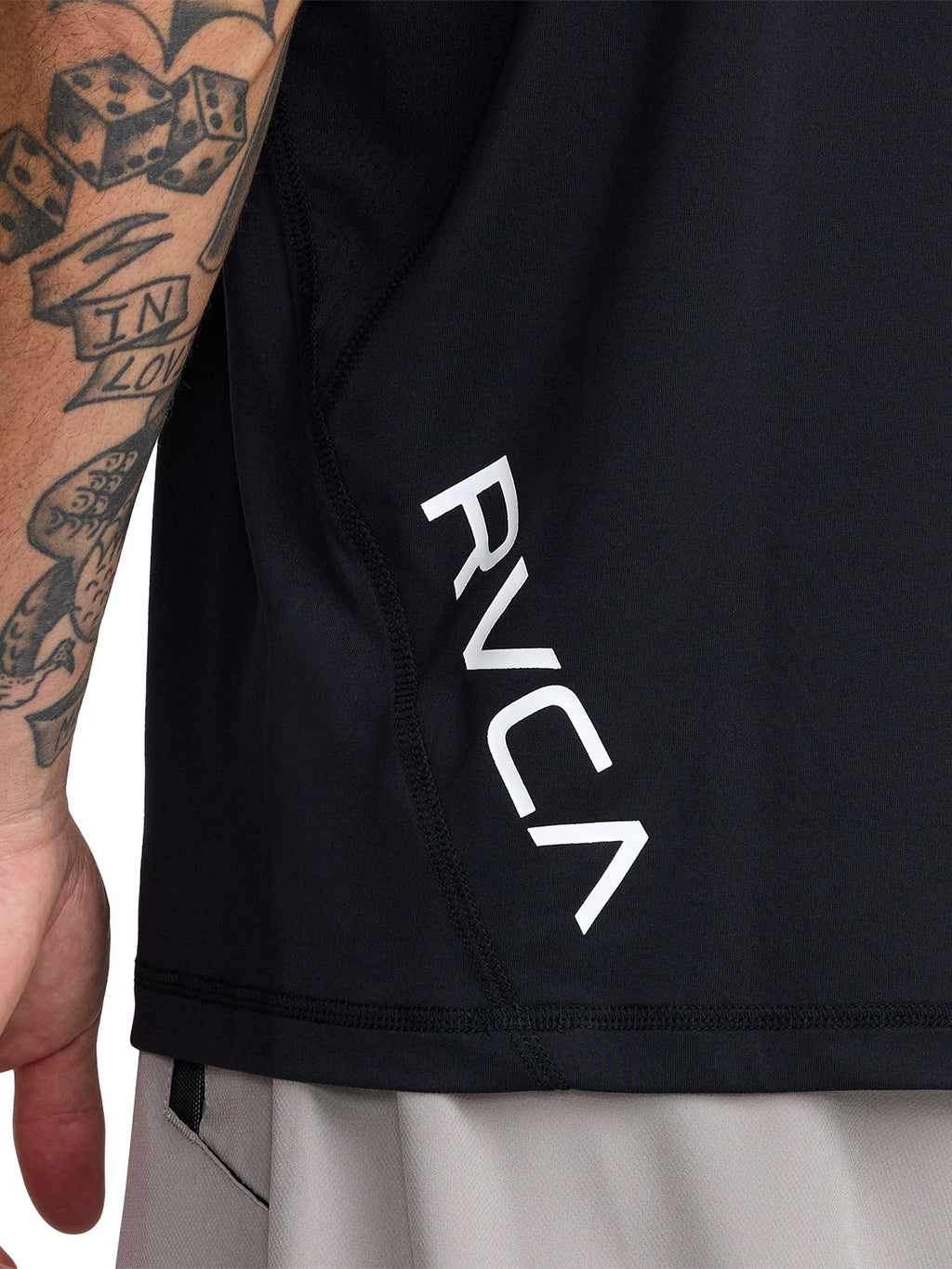 Black short-sleeve polo shirt with a black RVCA logo printed vertically near the lower left side. Back Close Up View