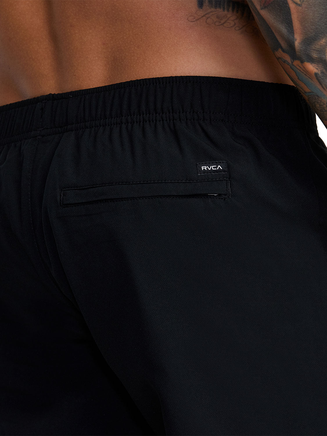 Black athletic shorts with a small white logo patch on the back pocket. Back  Close Up View.
